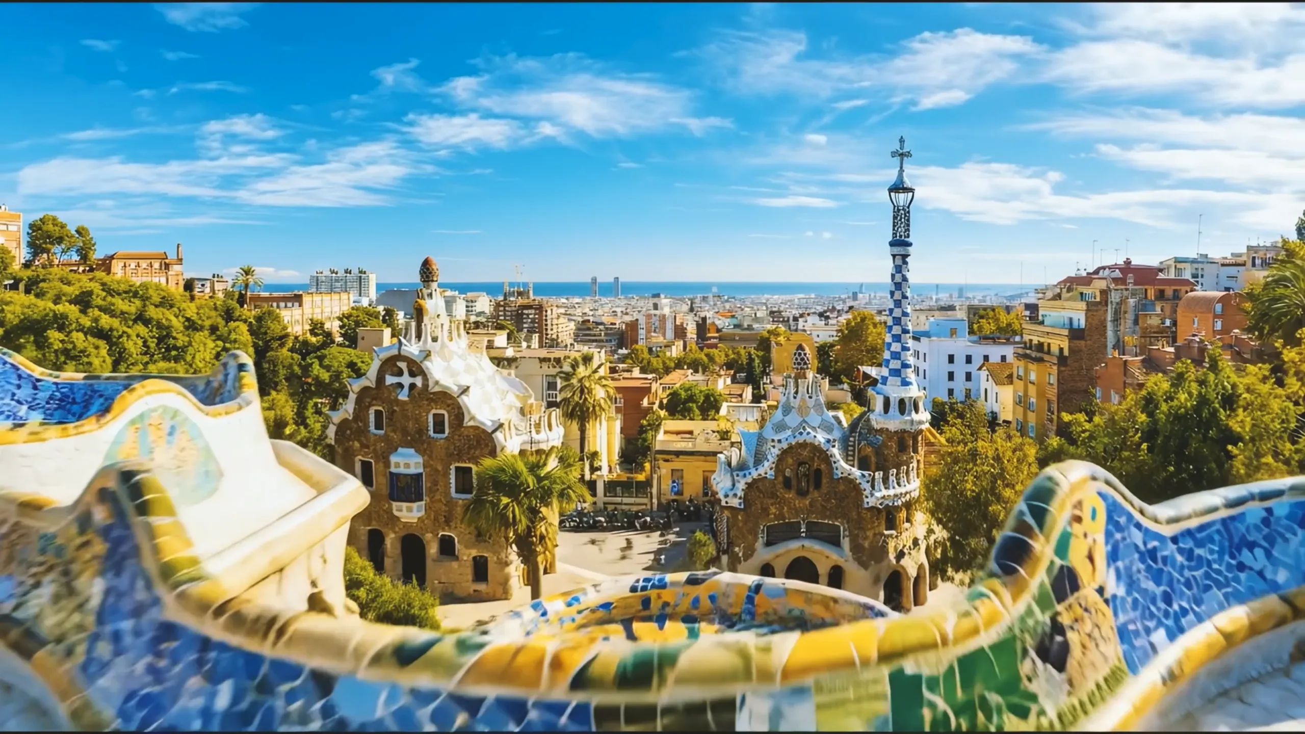 Blick über den Park Güell in Barcelona mit Mosaiken und Stadtpanorama bis zum Meer
