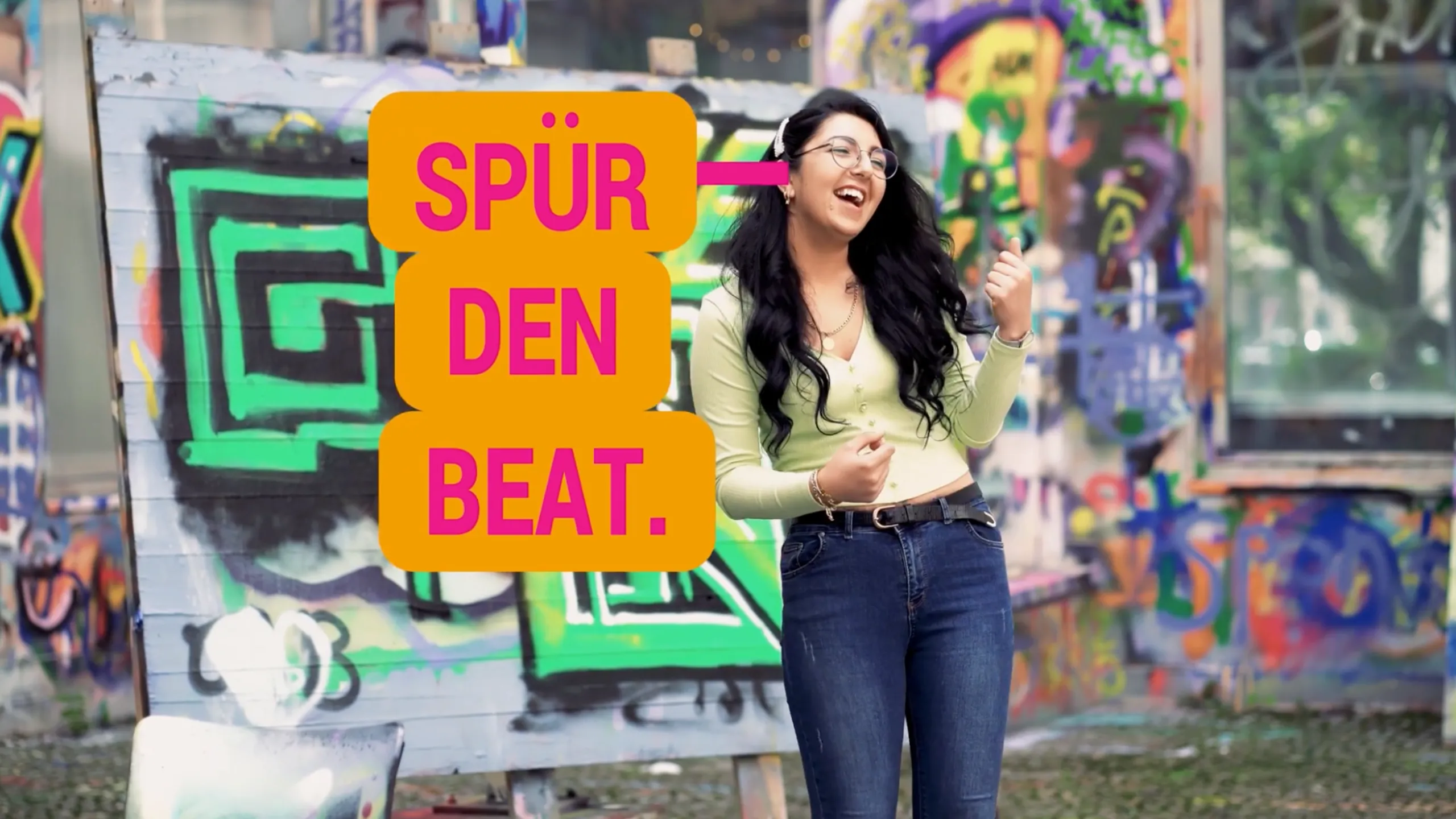 Frau vor urbaner Kulisse mit Text „Spür den Beat“ – moderne Kampagne zur Mitarbeitergewinnung Pflege