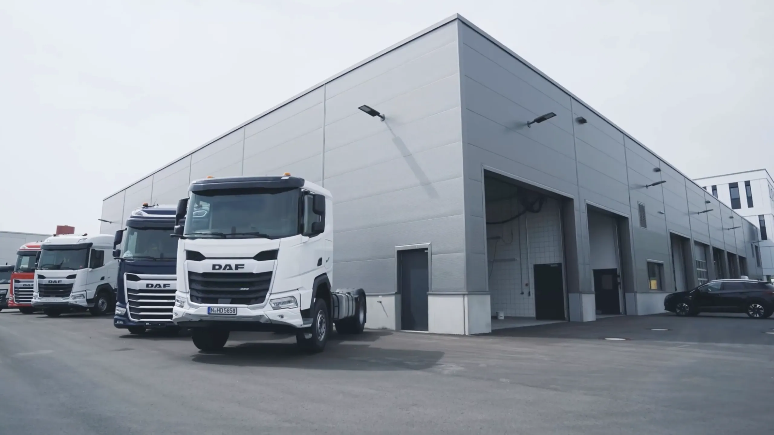 Moderne LKW-Werkstatt mit mehreren Servicehallen und abgestellten DAF-Lkw vor dem Gebäude – truckcon Werkstatttechnik im Einsatz